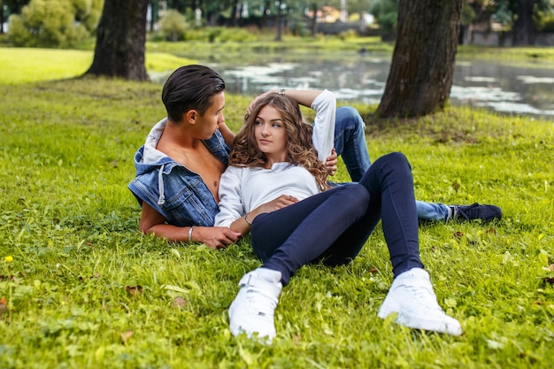 Impresionante pareja casual tumbada en el campo de hierba en el parque.