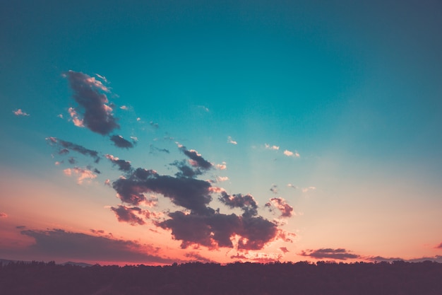 Foto impresionante puesta de sol de color rosa sobre el bosque con nubes y rompiendo los rayos del sol.