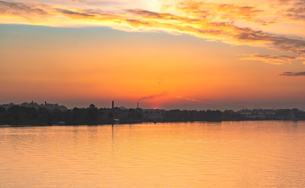 Impresionante puesta de sol sobre el río y sobre el sitio de la ciudad industrial hora dorada en el cielo