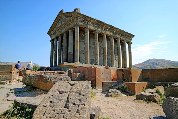 Impresionante templo pagano histórico de Garni con una antigua cruz de piedra en su base, ubicado en el pueblo de Garni, Armenia