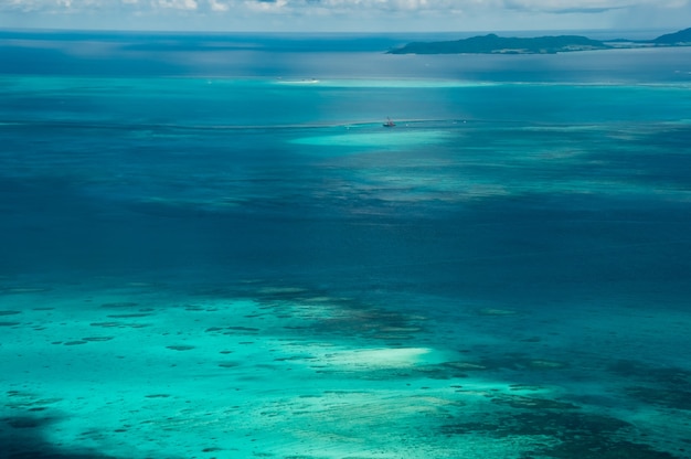 Impresionante vista del avión, arrecifes de coral, mar azul y verde claro, isla en el fondo.