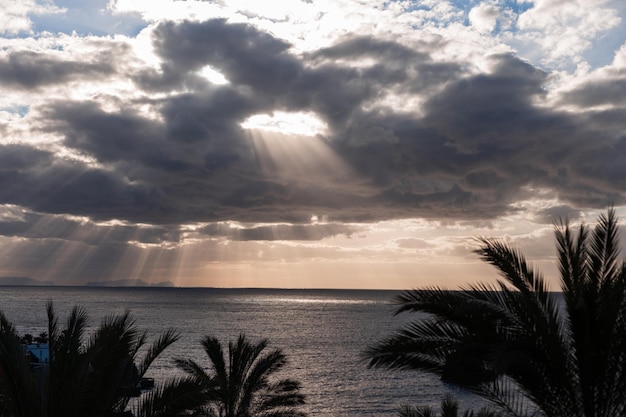 Foto impresionante vista del cielo con nubes y luz solar atravesando la nube isla de madeira hermosa vista al mar con palmeras