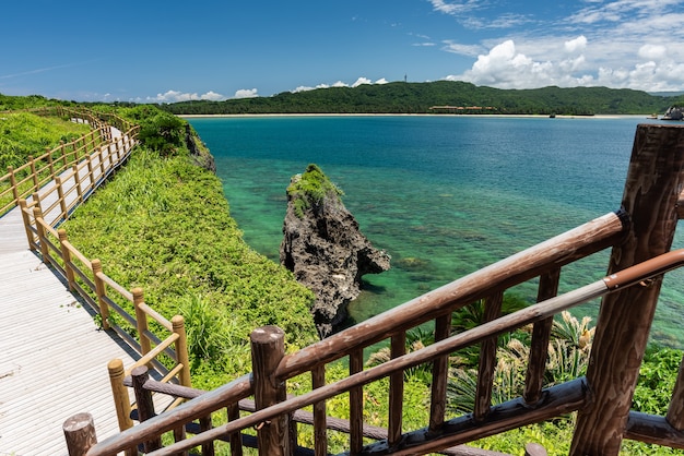 Impresionante vista desde una escalera de madera a la playa de Tsukigahama. Camino de madera, mar verde esmeralda, vegetación costera.