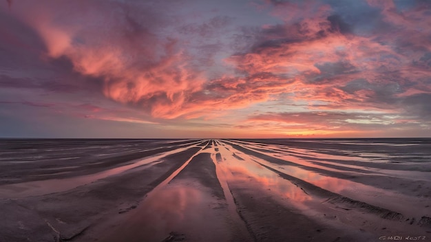 Foto impresionante vista de la llanura de barro del waddenzee durante la marea baja bajo un increíble cielo de puesta de sol con nubes