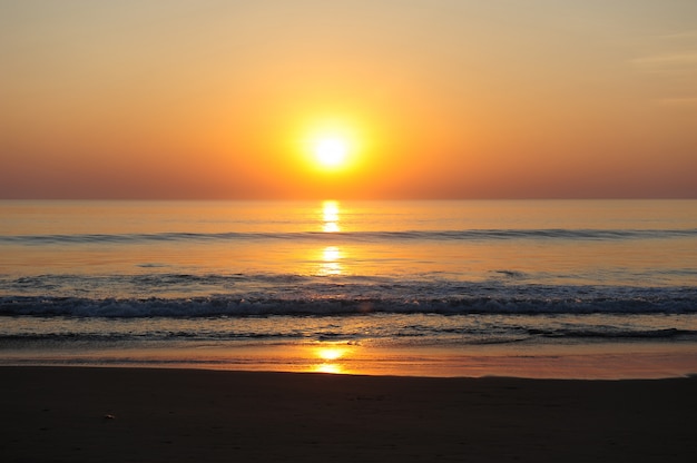 Impresionante vista del mar en los rayos del sol poniente, la luz del sol rojizo se refleja en el agua.