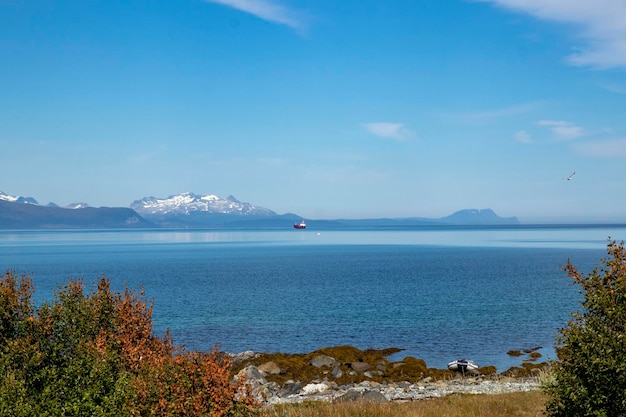 Impresionante vista de las montañas y los vados en Noruega x Alattervik barco rojo