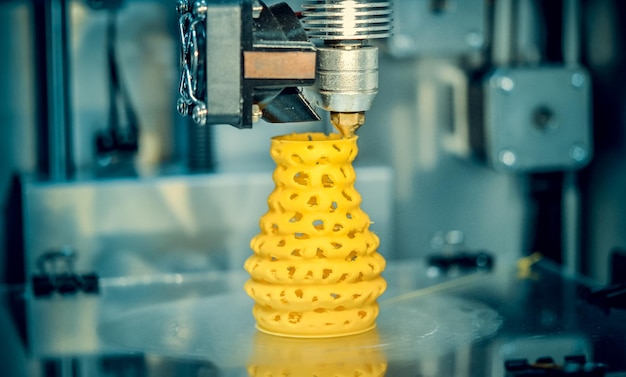 Impresora 3D imprimiendo objetos forma amarilla primer plano