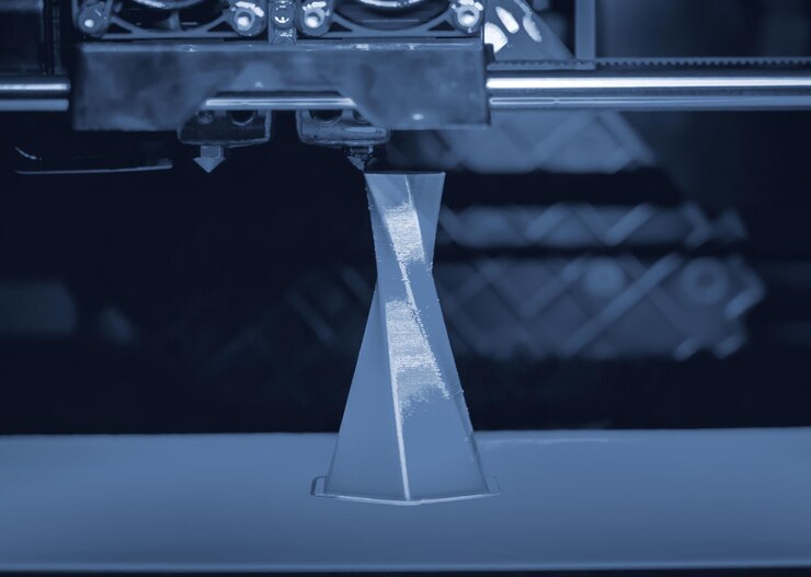 Foto impresora 3d que imprime volumen aislado objeto triangular color gris azul sobre la base de fondo azul y negro primer plano tecnología de impresión 3d moderna tecnología aditiva moderna progresiva