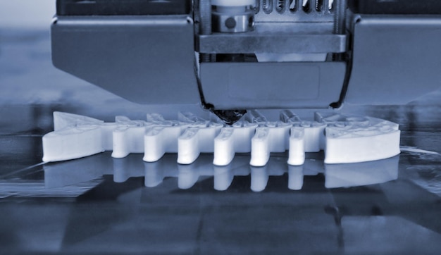 Impresora 3D que trabaja y crea un objeto a partir del primer plano de plástico fundido en caliente Impresora 3D tridimensional automática que realiza un prototipo de modelado de plástico en laboratorio Color gris azul