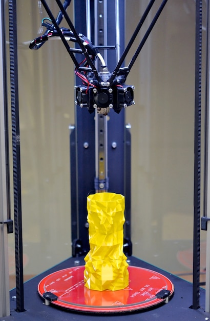 Impresora 3d de tres ejes y modelo amarillo en ella