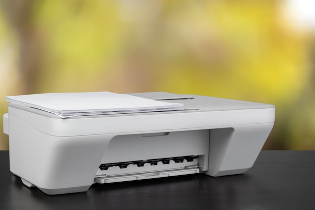 Impresora láser compacta en el escritorio negro contra el fondo borroso