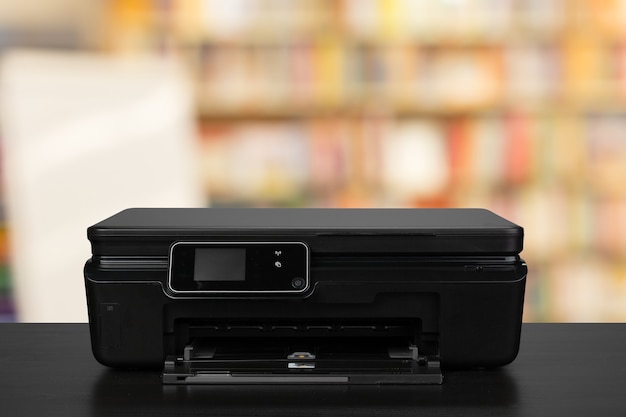 Impresora láser compacta en el escritorio negro contra el fondo borroso