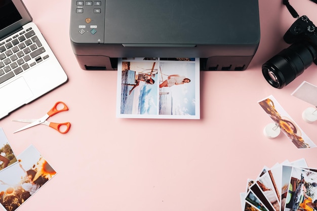 Impresora portátil y cámara en la mesa de cerca imprimiendo fotografías
