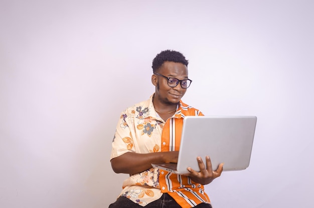 Foto impressionado jovem negro sentado sorrindo segurando usando laptop em suas mãos