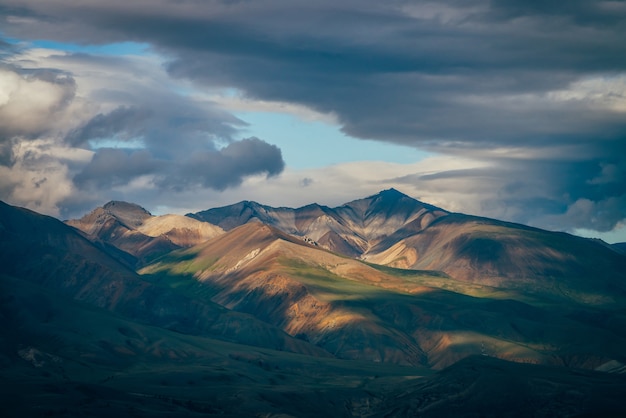 Impressionante paisagem montanhosa com grandes montanhas e desobstrução azul no céu nublado em tempo nublado.