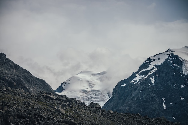 Impressionante paisagem montanhosa com o topo de uma grande montanha de neve em céu nublado. Cenário nublado atmosférico com alta montanha com geleira. Grandes montanhas com neve em nuvens baixas. Belas montanhas nevadas.