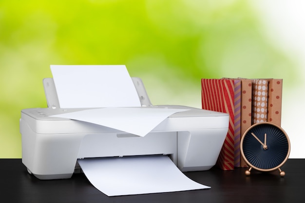 Foto impressora doméstica compacta na mesa com livros contra um fundo desfocado