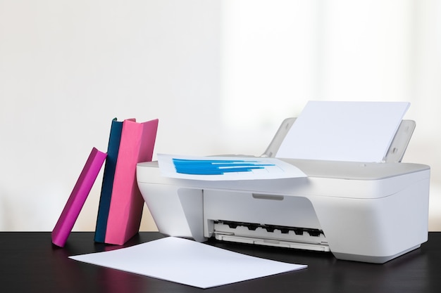 Impressora doméstica compacta na mesa com livros contra um fundo desfocado