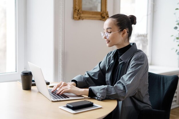 Imprime texto en el teclado de la computadora portátil Una mujer usa una computadora en una mesa El gerente con anteojos