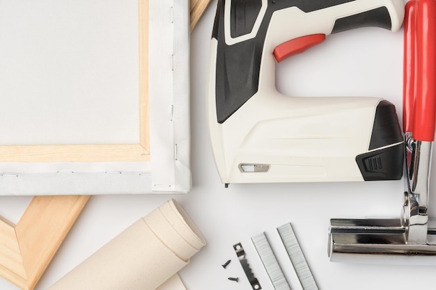 Imprimir uma foto em tela Equipamento de estiramento de tela Pinças de rolo de tela macas de madeira e uma pistola grampeadora em um fundo branco vista superior