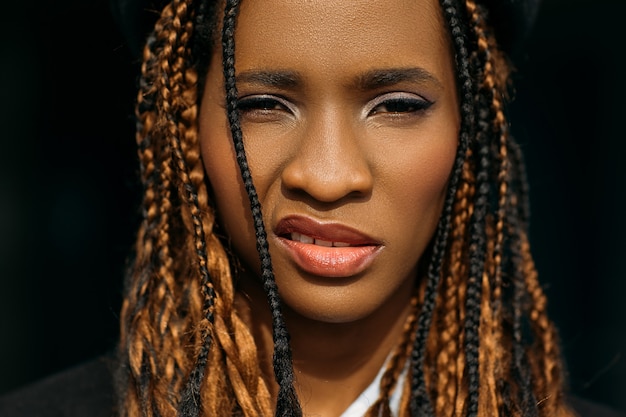 Foto impudente mujer afroamericana. cabello elegante. expresión facial insolente sobre fondo negro, estilo de vida juvenil moderno, concepto engreído