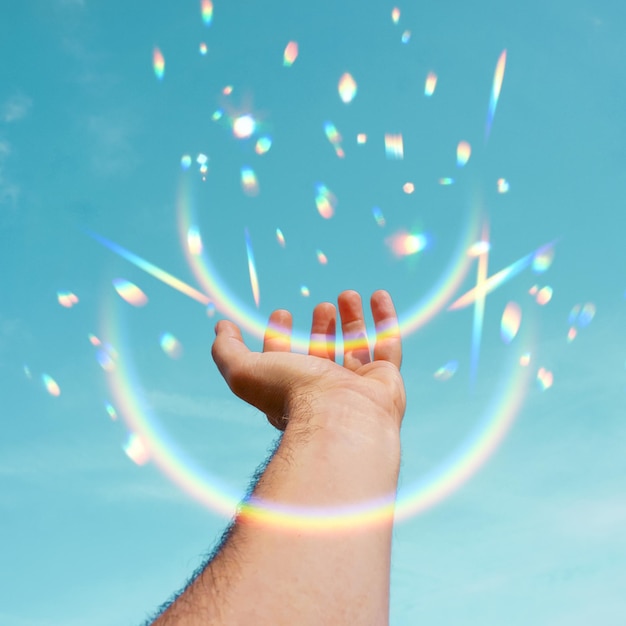 in den blauen Himmel erhobene Hand, die mit dem Sonnenlicht gestikuliert