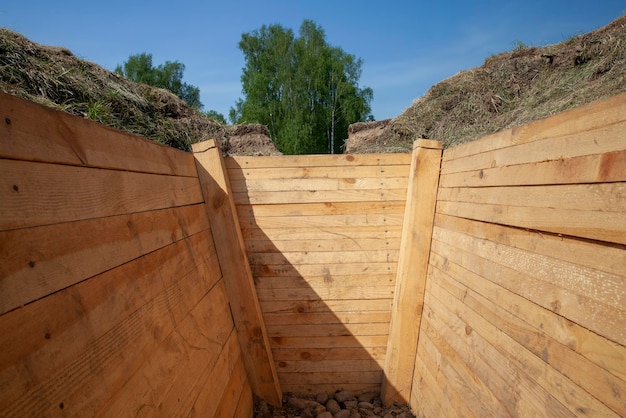 In den Boden gegraben und mit verbesserten Brettern verstärkter Graben