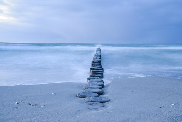 In den Horizont ragende Buhnen in der Ostsee Langzeitbelichtung mit gedeckten Farben