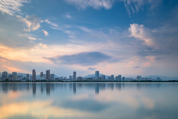 In der Abenddämmerung spiegelt der See die Nachtansicht der Stadt