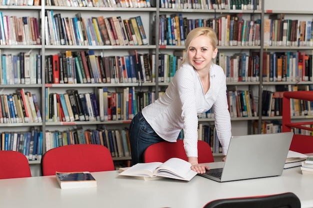 In der Bibliothek Hübsche Studentin mit Büchern, die in einer High School-Universitätsbibliothek arbeiten Geringe Schärfentiefe