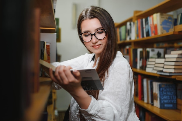 In der Bibliothek hübsche Studentin mit Büchern, die in einer Highschool-Bibliothek arbeiten