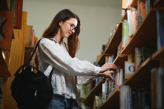 In der Bibliothek hübsche Studentin mit Büchern, die in einer Highschool-Bibliothek arbeiten