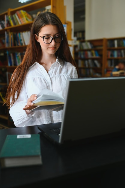 In der Bibliothek hübsche Studentin mit Büchern, die in einer Highschool-Bibliothek arbeiten