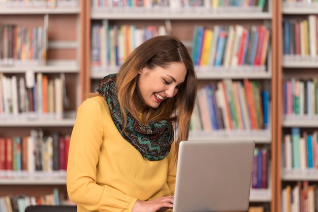 In der Bibliothek schöne Studentin mit Laptop und Bücher arbeiten in einer High School University Library geringe Schärfentiefe