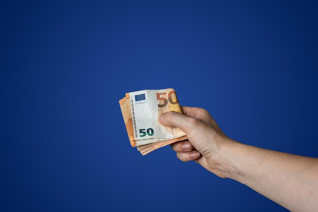 Foto in der hand ein bündel gefalteter 50-dollar-banknoten auf blauem hintergrund