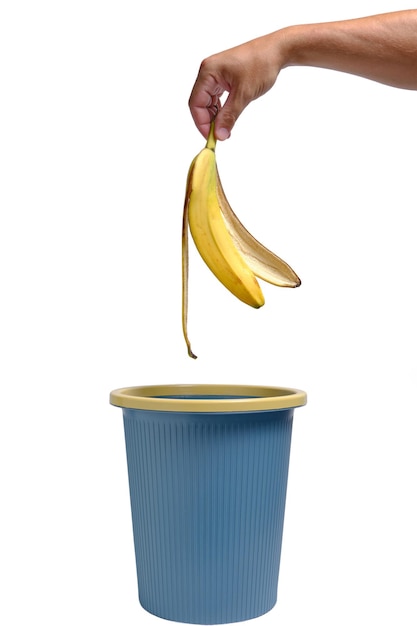 In der Hand eines Mannes wird Bananenschale in den Müll geworfen. Lebensmittelabfälle.