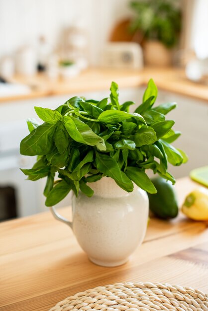 In der Küche stehen Spinatblätter in einer Vase. Gesundes Lebensmittelkonzept. Das Mädchen bereitet einen leichten gesunden Sommersalat zu.