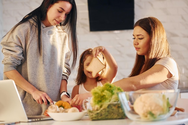 In der Küche Weibliches lesbisches Paar mit kleiner Tochter verbringt Zeit zusammen zu Hause