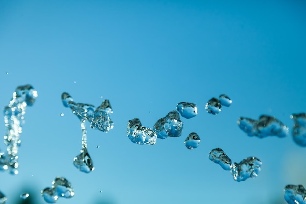 In der Luft gefrorene Wassertröpfchen mit Spritzern und Kettenblasen auf einem grünen, isolierten Hintergrund in der Natur. Klare und transparente Flüssigkeit, die Gesundheit und Natur symbolisiert