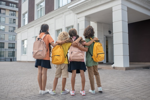 In der Nähe des Schulgebäudes. Schulkinder, die im Schulhof stehen und Schulgebäude betrachten