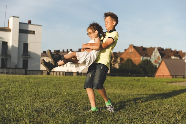 In der Natur rollt im Sommer ein Bruder seine Schwester in den Armen. sonniger Tag