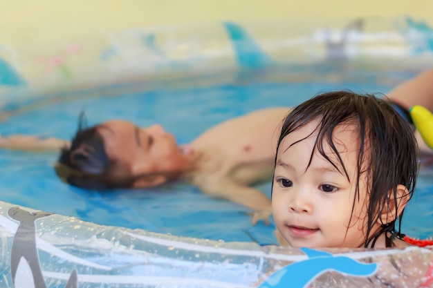 Foto in der sommersaison. asiatische kinder schwimmen und spielen im wasserpool.