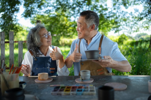 In der Töpferwerkstatt beschäftigt sich ein pensioniertes asiatisches Ehepaar mit Töpferwaren und Tonmalerei