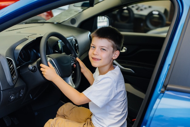 In einem Autohaus fährt ein glücklicher Junge ein neues Auto. Autokauf.