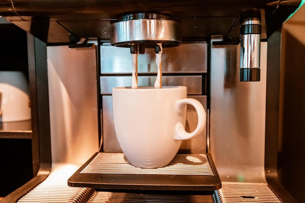 In einem Café wird Kaffee in eine Tasse gegossen Macchiato- und Kaffeemaschinenkonzept