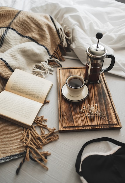 In einer französischen Presse gebrühter Kaffee und eine Tasse auf einem Holzbrett