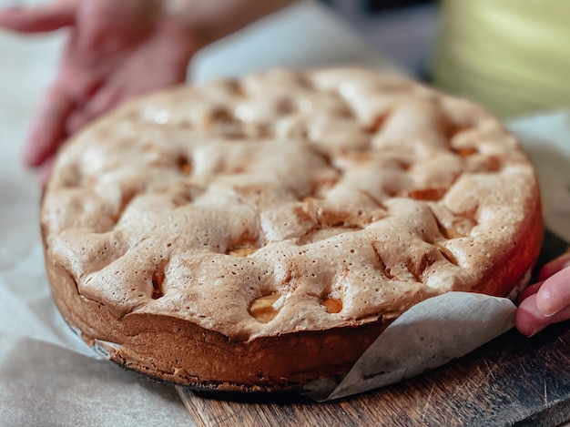 In einer Frau Hand frisch gekochten Biskuitkuchen mit Äpfeln Nahaufnahme. Ansicht von oben.