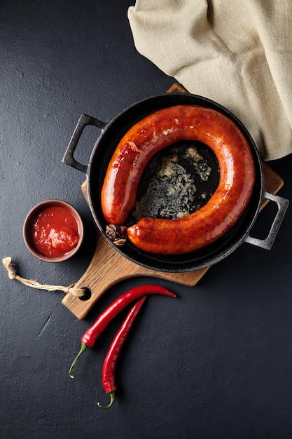 In einer gusseisernen Pfanne mit Ho zu einem Ring gerollte Schweinswurst gebraten