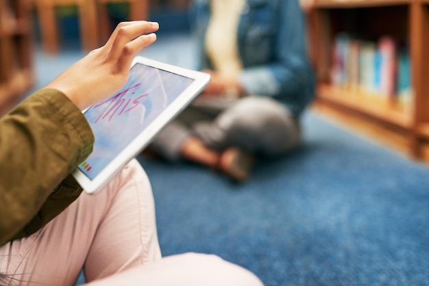 In einer Social-Media-Studienpause Nahaufnahme eines nicht wiederzuerkennenden Studenten, der ein digitales Tablet in der Bibliothek auf dem Campus verwendet