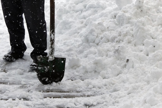 In einer Stadt schneit es und eine Person räumt die Straßen mit einer Schaufel